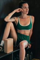 Brassière de sport Tennis Club verte vue de face, portée en position assise avec le short assorti.